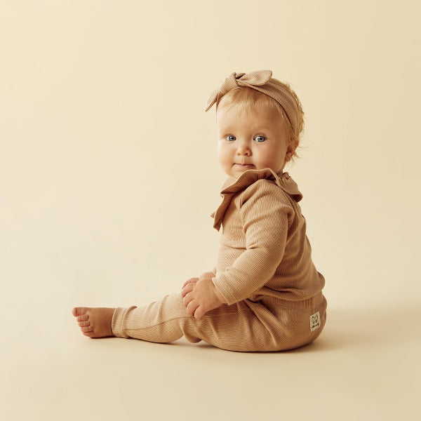 Side view of baby wearing WILSON + FRENCHY Fawn Organic Ruffle Top