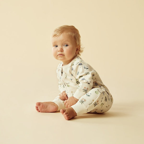 Baby sitting wearing WILSON + FRENCHY Petit Garden Organic Zipsuit with Feet
