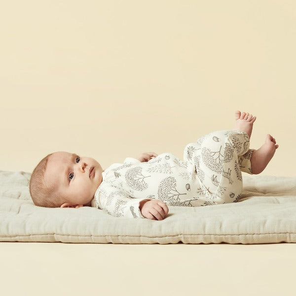 Baby lying down wearing WILSON + FRENCHY Woodland Organic Zipsuit with Feet