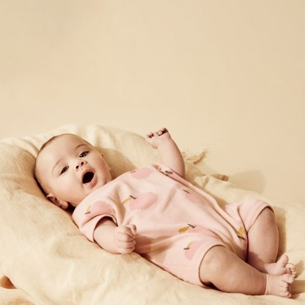 Baby lying down wearing WILSON & FRENCHY Just Peachy Organic Knitted Growsuit