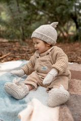 Baby sitting on rug wearing ACORN Cottontail Booties Oatmeal and Beanie 