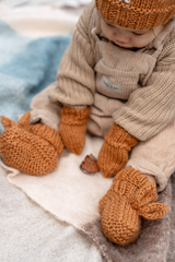 Baby sitting on rug wearing ACORN Cottontail Booties Caramel