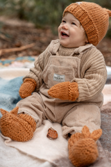 Baby sitting on rug wearing ACORN Cottontail Booties Caramel