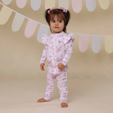 Child wearing a pink floral onesie against a neutral background with decorative elements.