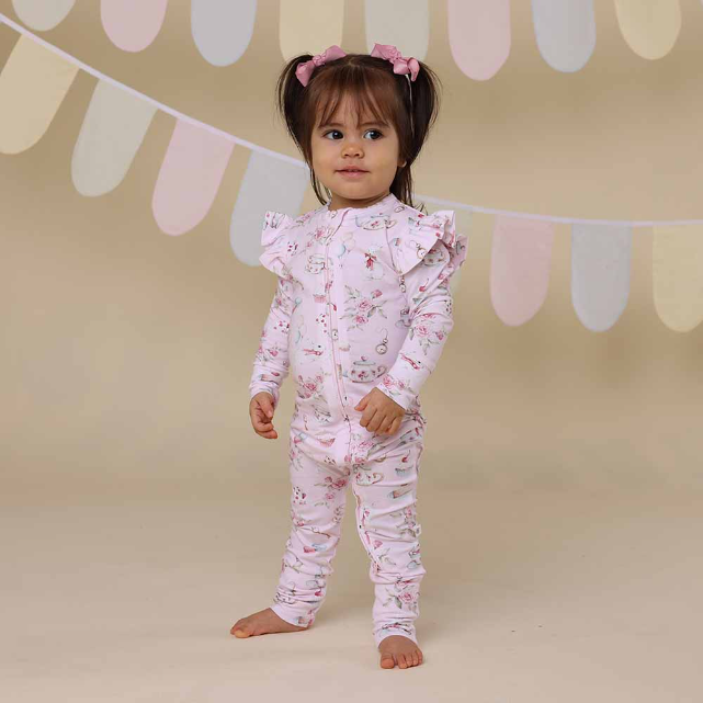 Child wearing a pink floral onesie against a neutral background with decorative elements.