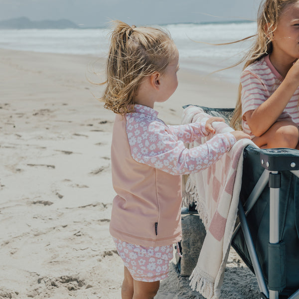 Child at beach wearing CRYWOLF Baby Swim Short & Rash Vest - Ditsy Floral - side view