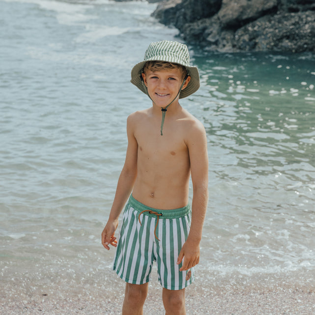 Boy at beach wearing CRYWOLF Reversible Bucket Hat - Coastal Stripe and boardshorts