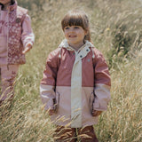 Child standing in tall grass wearing CRYWOLF Explorer Jacket Blush Rosewood