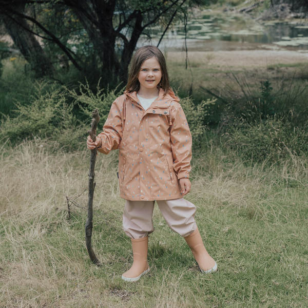 Child wearing CRYWOLF Play Jacket Rain Drops, Dusty Pink Rain Overalls and Terracotta Rain Boots