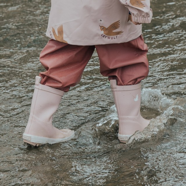 Child splashing in water wearing CRYWOLF Rain Boots Dusty Pink