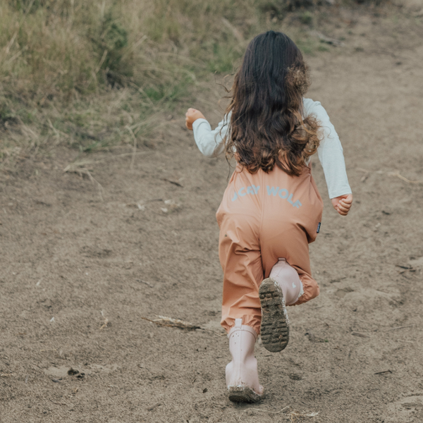 Back view of child running wearing CRYWOLF Rain Overalls Terracotta and Dusty Pink Rain Boots