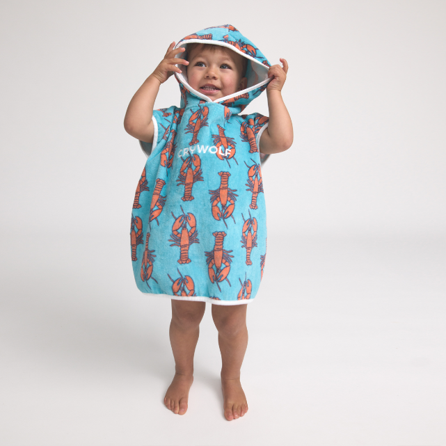 Child wearing a blue hooded towel with orange lobster patterns on a white background