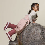 Child lying against rock in her CRYWOLF Rain Overalls Dusty Pink