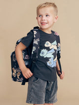 Child wearing the Huxbaby Super Dino backpack and tee