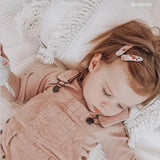 Child lying down with JOSIE JOAN'S Little Penny Hair Clips - Limited Edition in her hair