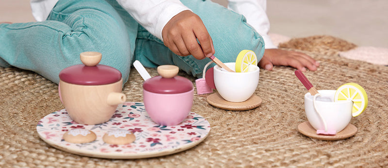 Child sitting on floor playing with JANOD Tea Set