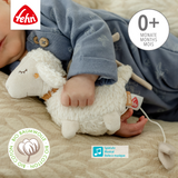 Child playing with a plush toy, wearing blue pajamas, on a beige surface with Fehn branding.