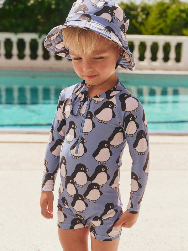 Toddler wearing the HUXBABY Percy Zip Shortie Rashsuit and matching swim hat