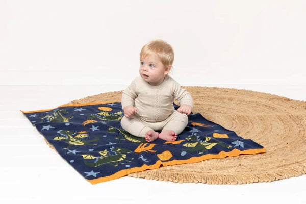 Baby sitting on INDUS DESIGN Dakota Dragon Baby Blanket