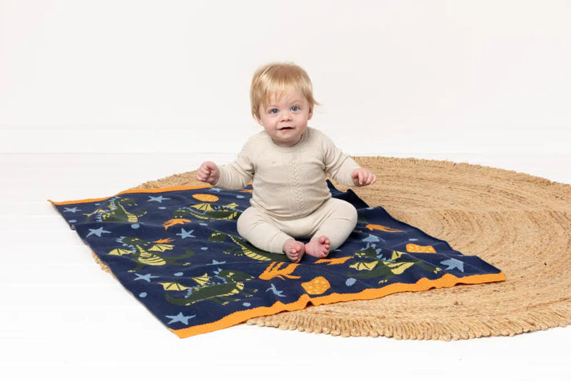 Baby sitting on INDUS DESIGN Dakota Dragon Baby Blanket