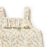 Detail view of ruffle neckline and shoulder straps on Lemon Leaf-patterned baby romper on a white background