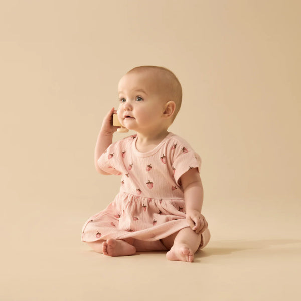 Baby in a pink dress sitting on a beige background