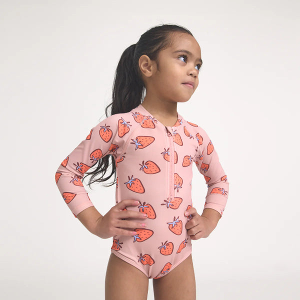 Child wearing a strawberry-patterned pink long-sleeve swimsuit on a white background