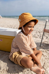 TODDLER SITTING ON SAND WEARING ACORN Terry Towelling Bucket Hat - Caramel SIDE VIEW