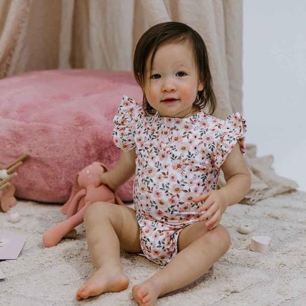 Toddler sitting on the floor wearing SNUGGLE HUNNY Spring Floral Short Sleeve Organic Bodysuit