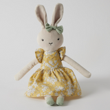 Stuffed bunny toy with a yellow floral dress and green bow on a white background