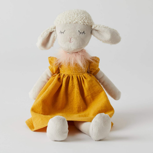 Stuffed toy sheep in a yellow dress on a white background