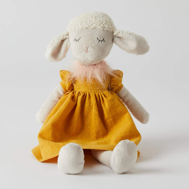 Stuffed toy sheep in a yellow dress on a white background