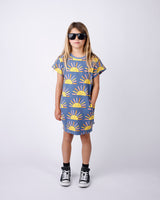 Child wearing a dress with sun pattern and sunglasses on a white background
