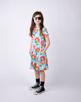 Young girl wearing a light blue floral dress and sunglasses on a white background