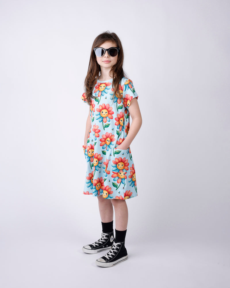 Young girl wearing a light blue floral dress and sunglasses on a white background