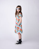 Young girl wearing a floral dress and sunglasses on a white background