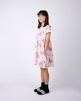 Young girl wearing a pink dress with unicorn print on a white background