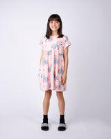 Young girl wearing a pink dress with unicorn print on a white background
