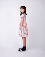 Side view of a Young girl wearing a pink dress with unicorn print on a white background