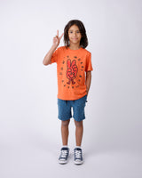 Child wearing an orange t-shirt with a peace sign design and denim shorts on a white background