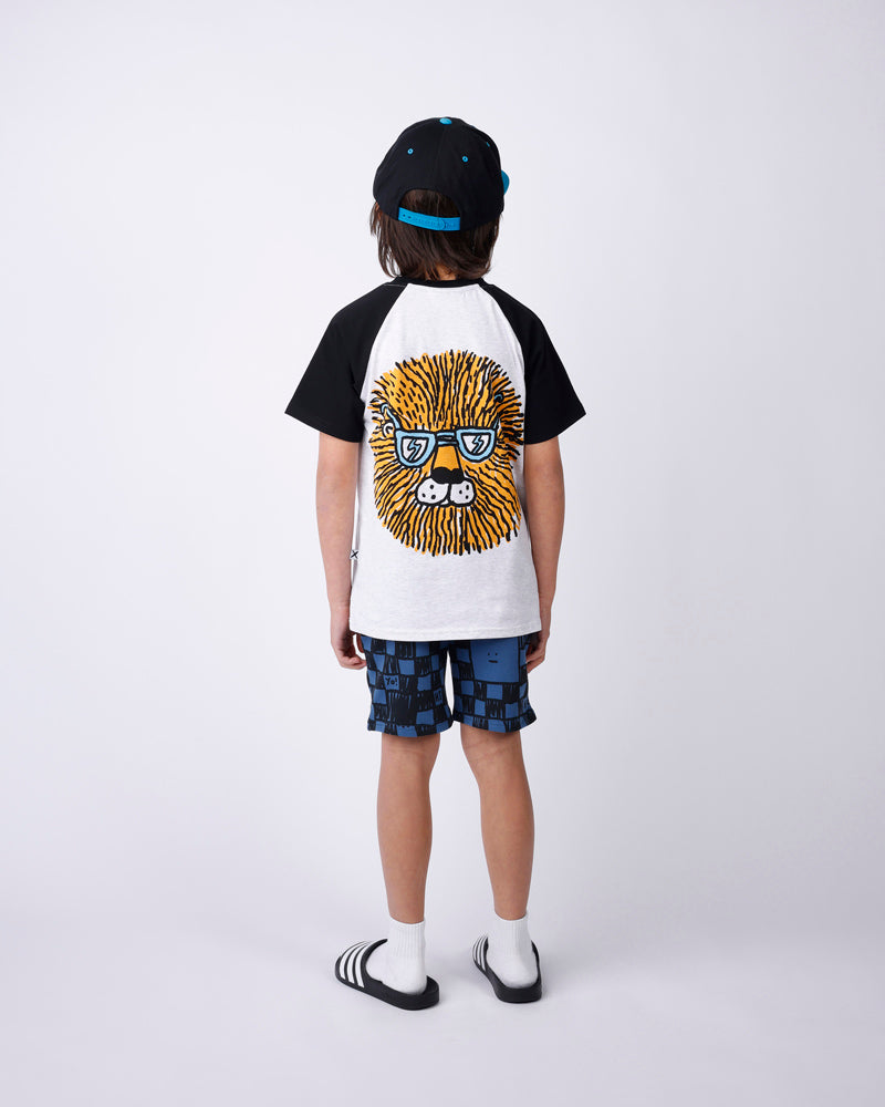 Child wearing a black and white tee shirt with a graphic design, checkered shorts, and a cap on a white background