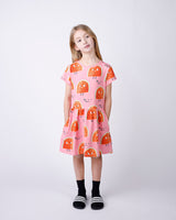 Young girl wearing a pink dress with watermelon pattern on a white background