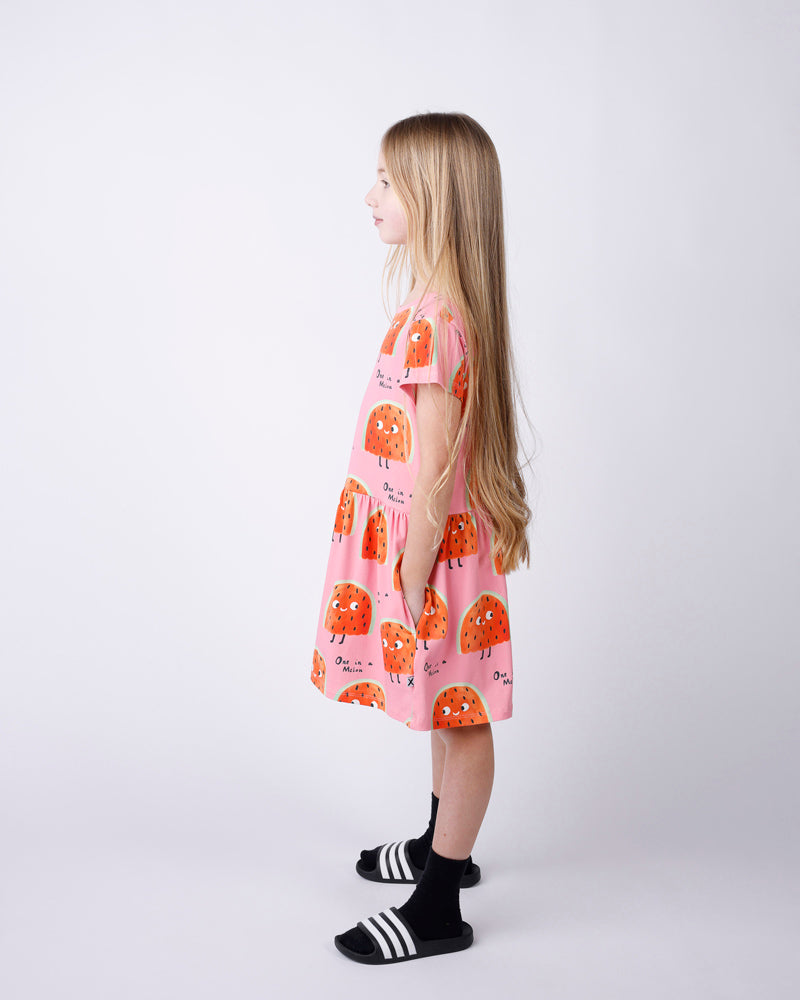Young girl wearing a pink dress with orange patterns on a white background