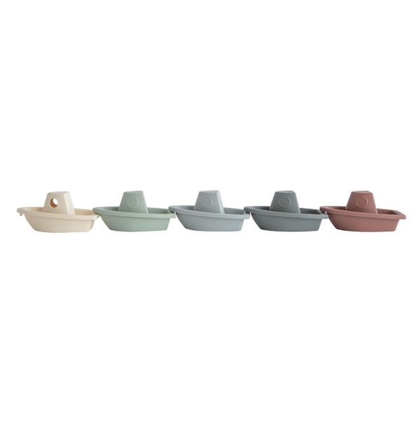 Five small boats in different pastel colors on a white background
