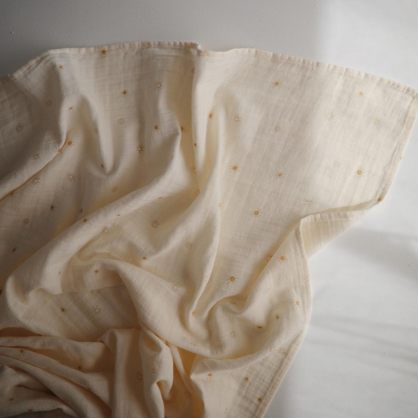 Beige fabric with small patterns of golden suns on a light background