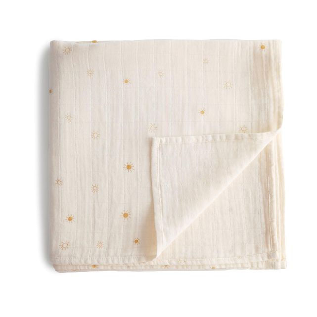 Folded beige fabric with small yellow sun print on a white background