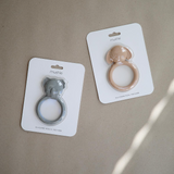 Two silicone ring teether products on their packaging with 'mushie' branding on a beige background.