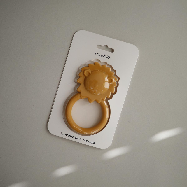 Silicone lion teether packaged in a white card with 'mushie' branding against a gray background