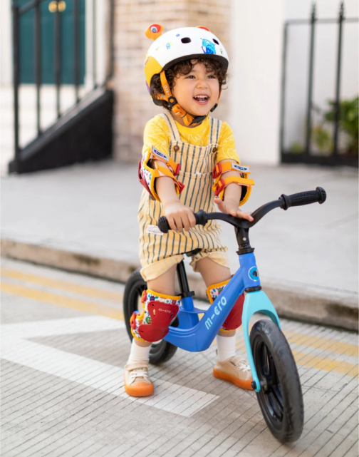 Child riding a balance bike on a sidewalk