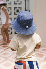 Back view of child wearing a blue hat with fishing them print